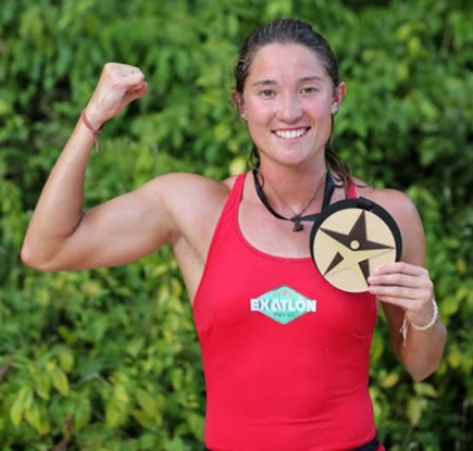 En la imagen se muestra a Mati Álvarez, una heptatleta sosteniendo una medalla con su brazo derecho y en el brazo izquierdo esta  flexionado a 90°, reflejando fuerza.Mati  ha ganado múltiples campeonatos y récords. Su carrera en Exatlón y como presentadora inspira a mujeres a romper 